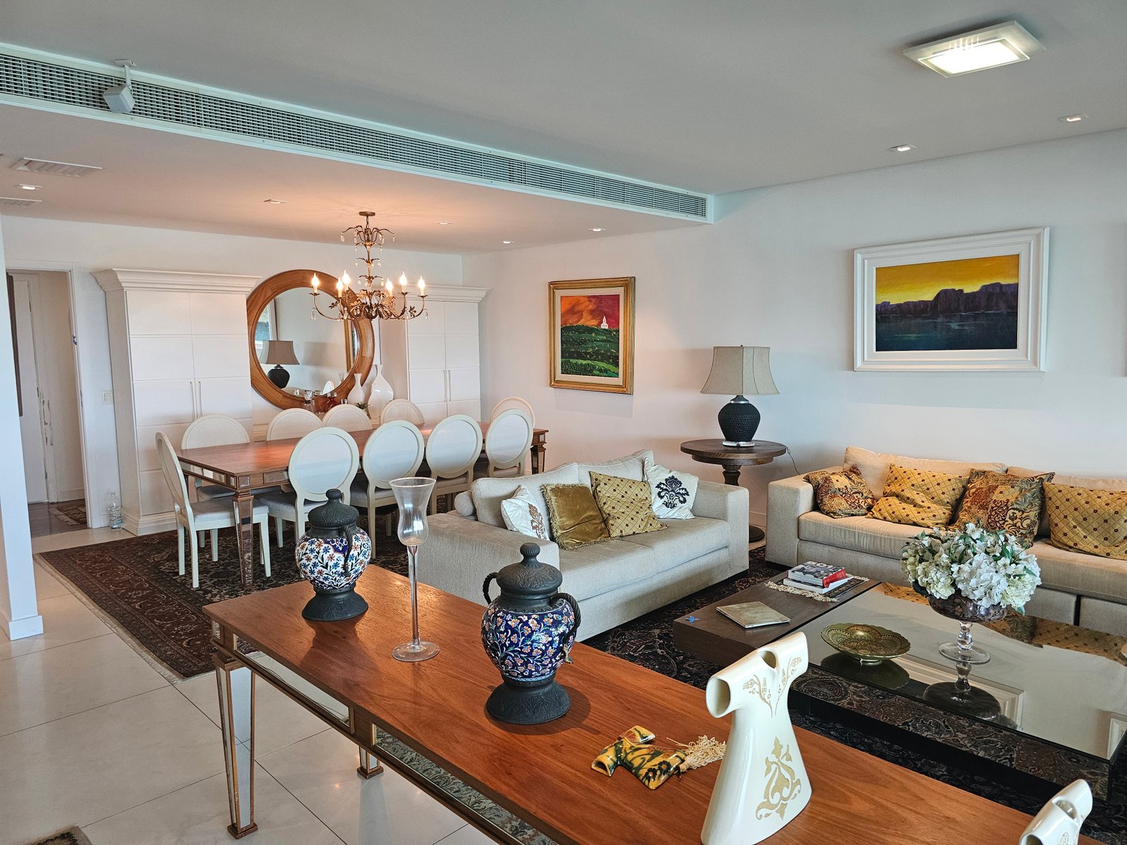 Sala de jantar integrada à sala de estar com lustre dourado e decoração clássica